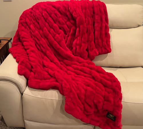 Reviewer's vibrant Hugs Red Blanket with a plush texture draped over a cream sofa.