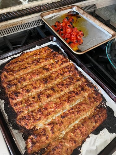 Reviewer's browned Halal Beef Ground Meat, cooked on a sheet pan next to roasted tomatoes on a stovetop.