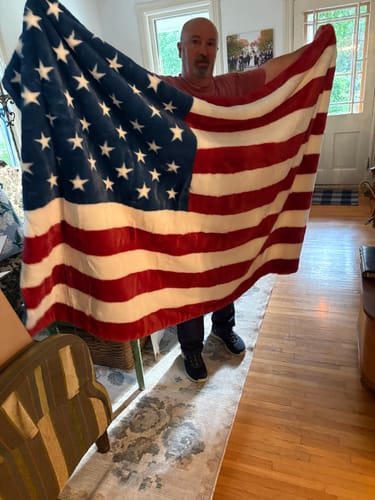 Reviewer holding up the large, plush Lush Flag Blanket to show its full size and patriotic design.