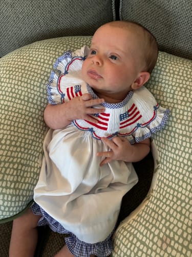 Customer's baby wearing the Flag Smocked Bloomer Set featuring smocked American flags.