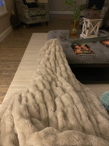 A reviewer's plush, gray Hugs Tranquil Dove Blanket draped in a living room.