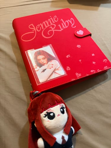 Customer's red Jennie Four Panel Card Album, with a photocard in the front sleeve and a plush doll resting beside it.
