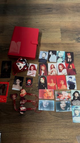 Customer's Jennie × Miniso Small Card Set and merchandise, including a red binder and photocards, displayed on a wooden surface.