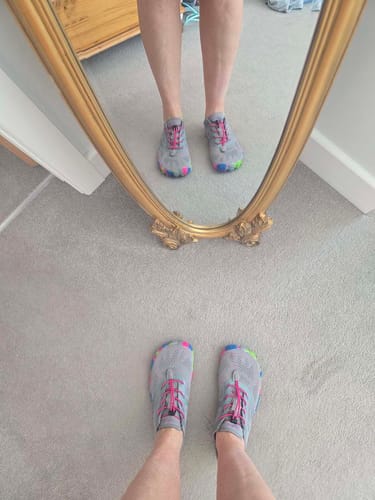 Customer wearing grey Smart II - Barefoot Shoes with colorful toes, seen directly and in a mirror reflection.