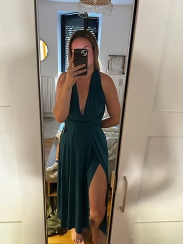 Une cliente portant la robe longue CECILIA bleu canard, avec un décolleté plongeant et une fente sur la jambe.
