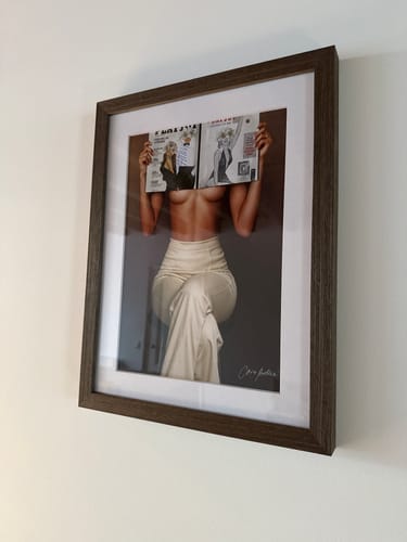 Customer's framed art hanging on a wall, showcasing the wide White Gallery Mat Board inside a dark wood frame.