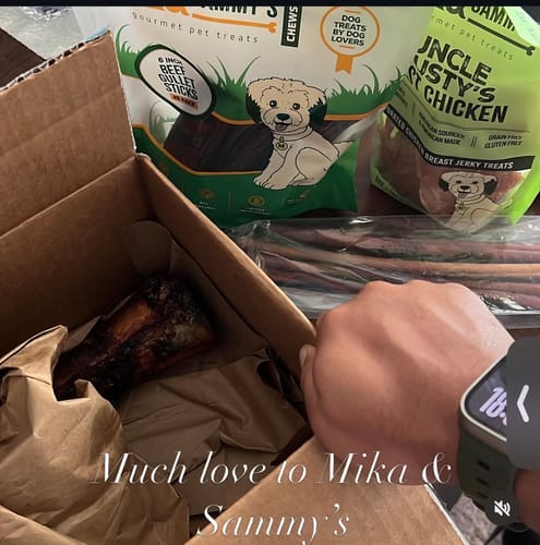 Reviewer unboxing the Large Dog Spring Treat Bundle, showing a large marrow bone and bags of treats.