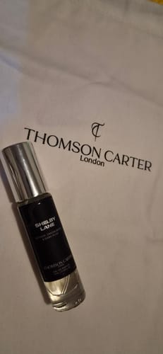 Customer's Shelby Lane Eau de Parfum bottle with a silver cap, resting on a white branded bag.