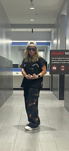 Reviewer standing in a hallway wearing the Camo Cargo Joggers in a baggy, relaxed fit.