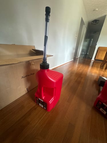 Customer's red Tuff Jug utility container standing on a wooden floor next to its shipping box.