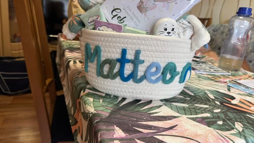 Customer's personalized Baby Knits white knitted basket featuring the name Matteo in blue yarn letters.