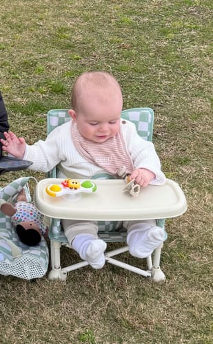 Customer's green checkered Parker baby chair v2 with a toddler playing with colorful toy spinners on the tray.