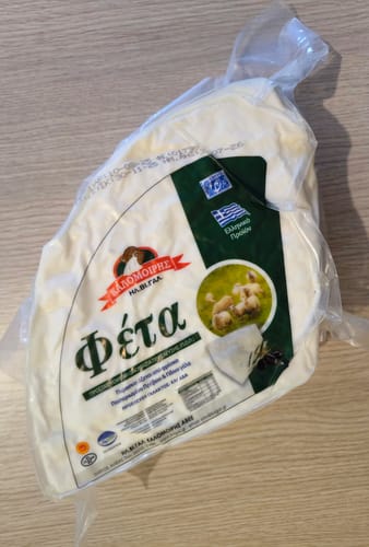 Customer's vacuum-packed, triangular wheel of Pyrgos Reserve Barrel-Aged Feta with visible Greek labeling and branding.