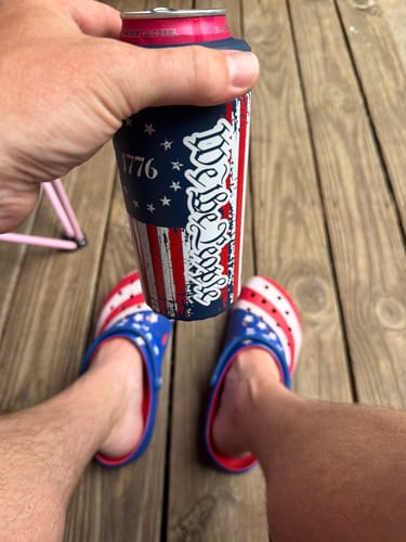 Customer's Universal Buddy can cooler with We The People design held in hand over wooden deck