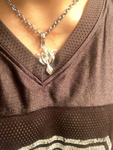 Customer's silver Tribal Cross Pendant worn on a metal chain around the neck against a dark mesh athletic jersey.