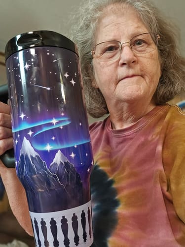 Customer's Nightfall Thicc Buddy mug with glowing mountain and sky illustration held by a person.