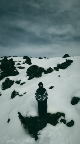 Reviewer standing in snowy mountain landscape, wearing gear while testing the moisture-wicking ski socks.