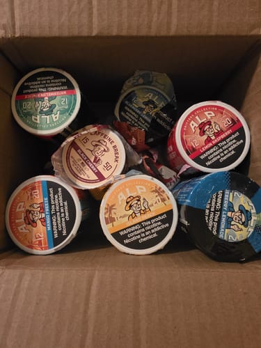 Customer's box containing several round Drifters Combo Pack tins with colorful labels