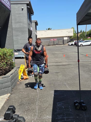 Customer's athlete walking with heavy dumbbells during a competition while using SuperCharged Honey for energy.