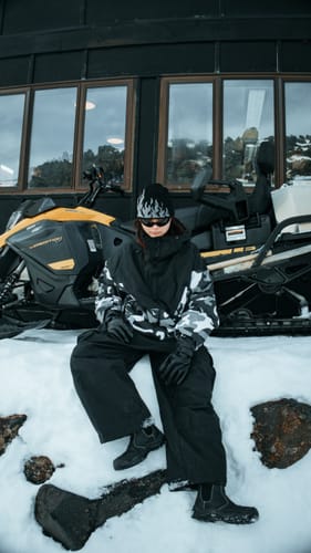 Reviewer's black flame beanie worn while sitting on a snowmobile in a snowy setting.