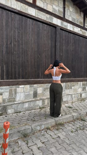 Customer's Haki Paraşüt Baggy Pantolon, a loose-fitting khaki pant, worn by a person outdoors near a stone wall.