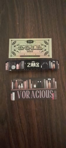 Customer's 2025 Book Challenge Voracious Bracelet, a Zox Goldie win, and packaging on a wooden table.