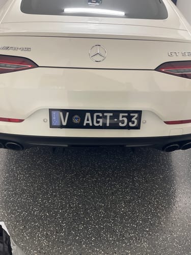 Customer's Angled Spacer Kit installed on a white car license plate frame.