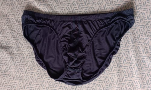 Customer's navy blue Modal Bikini Briefs lying flat on a patterned surface.