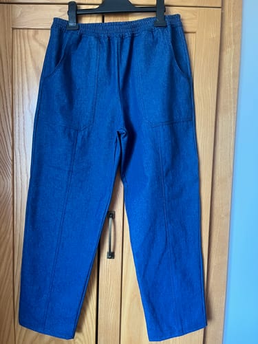 Reviewer's handmade blue denim trousers made from the 8oz Washed Denim Fabric, hanging on a hanger.