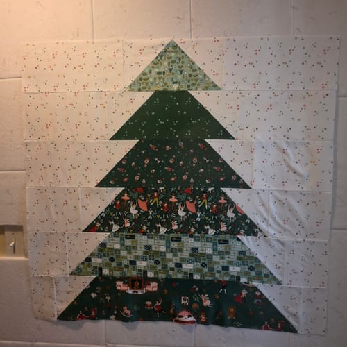 Customer's Presents & Pines Quilt Kit featuring a large green fabric tree wall hanging with festive patterns.