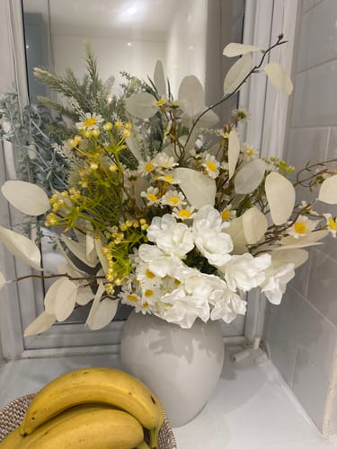 Customer's Faux Arrangement in a ceramic vase placed on a counter near two yellow bananas.