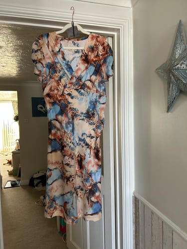 Customer's dress made from printed viscose fabric, featuring a blue and brown tie-dye pattern, hanging on a door.