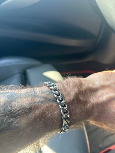 Reviewer's polished silver Cuban chain bracelet worn on their wrist, showing the link style.