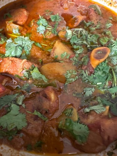 Customer's cooked Halal Lamb Shoulder stew in a savory red sauce topped with fresh cilantro.