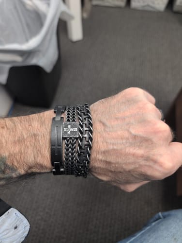 Customer's dark, interlocking Connected At The Cross bracelet worn on a wrist with other matching metal bracelets.