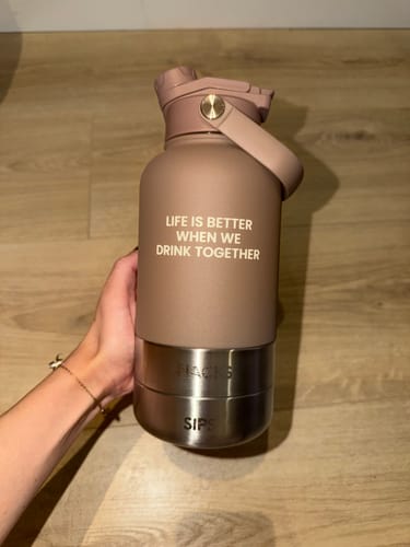 Customer's hand holding a matte brown Bowl Bottle 2.0 with a printed quote and metallic bowl attachments