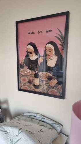Customer's framed HOLY TRINITY print hanging on a wall, featuring nuns eating pasta with wine.