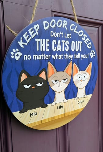 Customer's round blue Peeking Fluffy Cats Wooden Plaque hanging on a dark purple door.