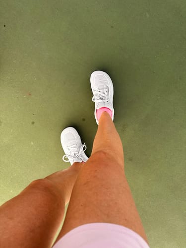 Customer's white CUURT Muuv court shoes being worn on a green pickleball court.