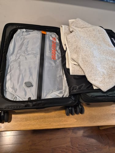 Customer's Aerless vacuum bag inside an open suitcase next to a fleece jacket.
