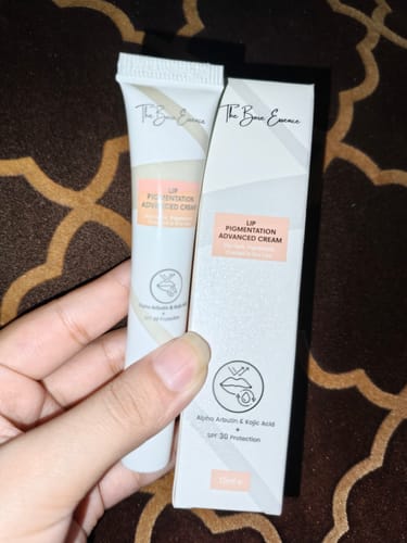 Customer's hand holding the Lip Pigmentation Cream tube next to its white packaging box.