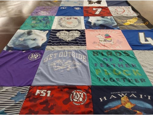 Customer's Project Repat T-Shirt Quilt laid flat, featuring a colorful grid of various graphic t-shirt designs.