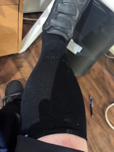 Customer's Eucalyptus Lyocell Compression Socks on leg, paired with a black shoe while sitting.