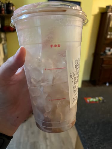 Customer's hand holding a plastic cup filled with ice, five hours after filling, showing lasting coldness.