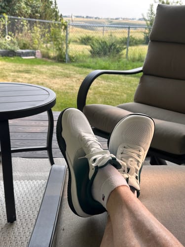 Reviewer's CUURT Muuv court shoes being worn while relaxing outdoors on a deck chair.