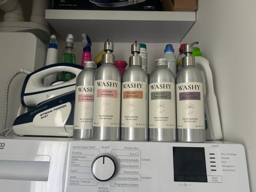 Customer's collection of five Washy laundry perfume bottles on a shelf above a washing machine.