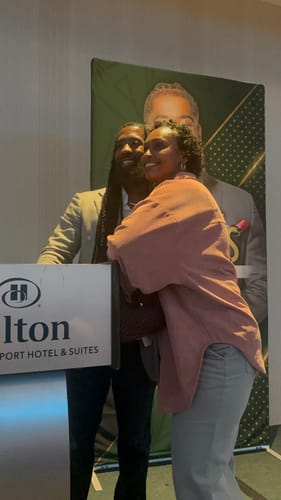 Customer's photo at the Heal My People Tour, posing with a speaker in front of an event backdrop.