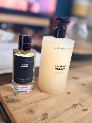 Customer's Lilium Blume perfume bottle and body wash bottle on a wooden surface.