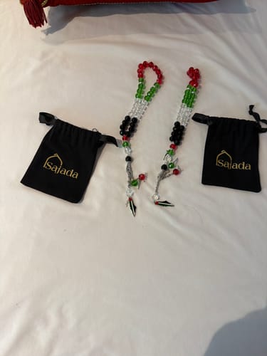 Reviewer's two Free Palestine prayer bead strings with red, green, black, and clear beads and two small black bags.