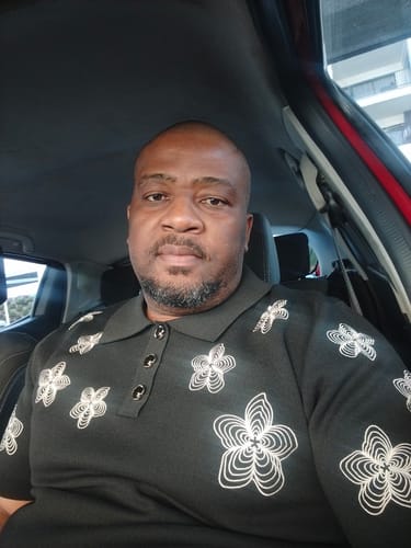 Customer's LFN020 knit top in black with a floral pattern, worn while sitting in a vehicle.